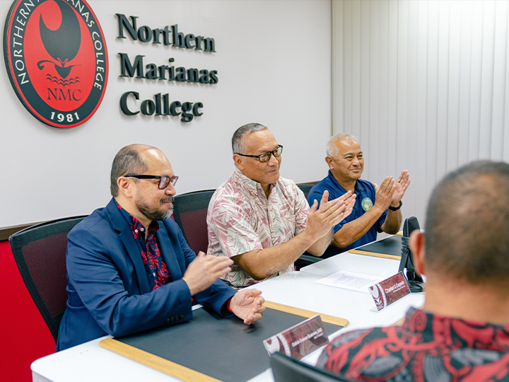 Northern Marianas College President Dr. Galvin S. Deleon Guerrero, left, shakes hands with NMC Board of Regents Chairman Charles V. Cepeda, center, as NMC Foundation Chairman Vicente Babauta, third right, and other members of the Board of Regents applaud in the NMC Board of Regents conference room on Thursday.